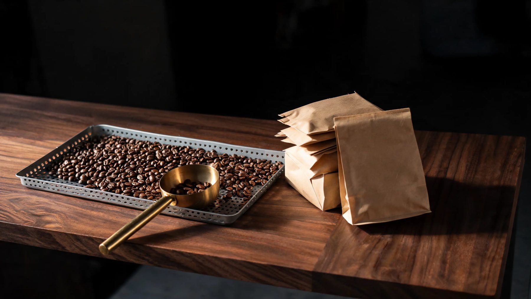 Roastery bench with a cooling tray of fresh beans and stacked kraft bags